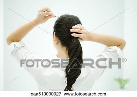Woman putting hair in ponytail, arms raised, rear view View Large Photo Image Stock Photo - Woman putting hair in ponytail, arms raised, rear view. Fotosearch