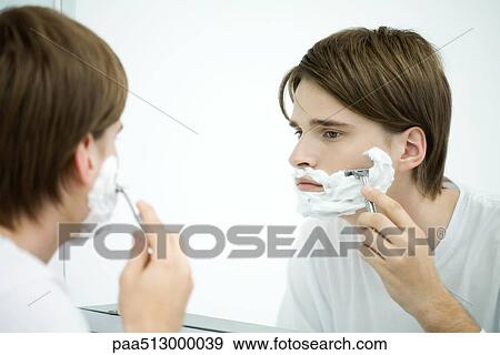 Young man looking at self in mirror, shaving View Large Photo Image Stock Photo - Young man looking at self in mirror, shaving. Fotosearch