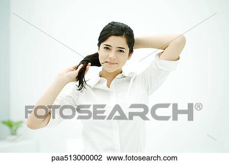 Young woman pulling back hair, holding hairpin in mouth View Large Photo Image Stock Image - Young woman pulling back hair, holding hairpin in mouth. Fotosearch