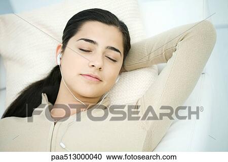 Young woman reclining, listening to MP3 player, eyes closed View Large Photo Image Stock Image - Young woman reclining, listening to MP3 player, eyes closed. Fotosearch