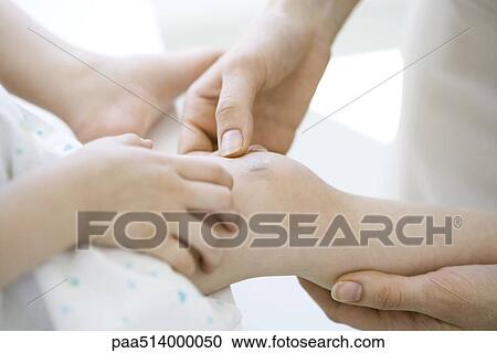 Adult placing adhesive bandage on child's knee, cropped view View Large Photo Image Stock Image - Adult placing adhesive bandage on child's knee, cropped view. Fotosearch