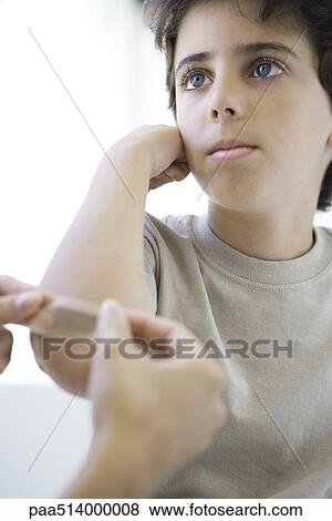 Boy having adhesive bandage applied to his elbow, cropped view View Large Photo Image Stock Photo - Boy having adhesive bandage applied to his elbow, cropped view. Fotosearch