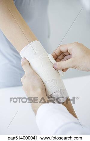 Doctor bandaging patient's arm, cropped view View Large Photo Image Stock Image - Doctor bandaging patient's arm, cropped view. Fotosearch