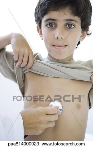 Stock Image - Doctor placing stethoscope on boy's chest, boy smiling at camera, cropped. Fotosearch