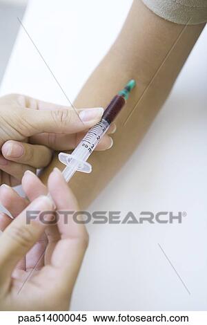 Stock Photography - Doctor taking patient's blood with syringe, cropped view. Fotosearch