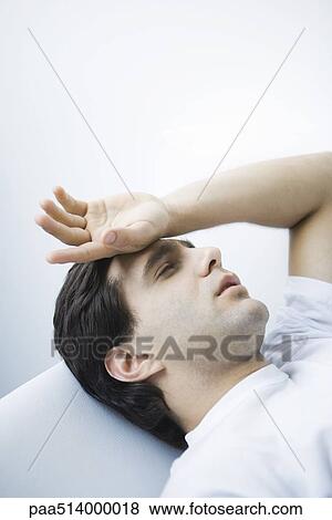 Man reclining with eyes closed, hand on forehead View Large Photo Image Stock Photo - Man reclining with eyes closed, hand on forehead. Fotosearch