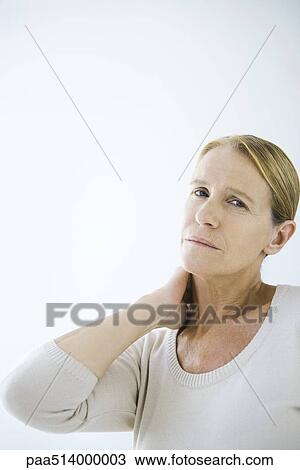 Stock Image - Mature woman rubbing her neck, looking at camera. Fotosearch
