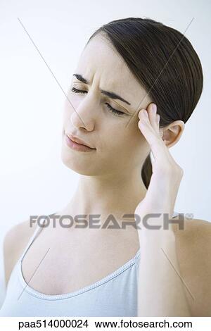 Picture - Woman massaging her temple and furrowing her brow, eyes closed. Fotosearch