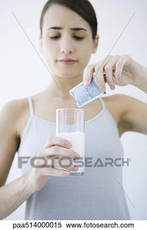 Stock Photography - Woman pouring effervescent medicine into glass of water. Fotosearch