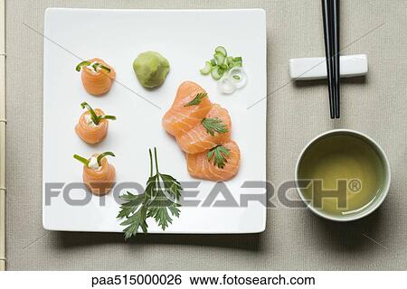 Assorted sushi arranged on large sushi plate with tea and chopsticks alongside View Large Photo Image Stock Photograph - Assorted sushi arranged on large sushi plate with tea and chopsticks alongside. Fotosearch