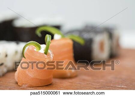 Stock Image - Cropped view of assorted maki sushi, focus on salmon in foreground. Fotosearch