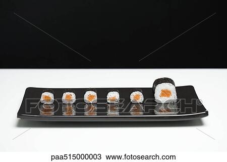 Stock Image - Maki sushi arranged on plate, one piece larger than the rest. Fotosearch