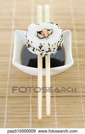 Maki sushi balanced on chopsticks over dish of soy sauce View Large Photo Image Stock Photo - Maki sushi balanced on chopsticks over dish of soy sauce. Fotosearch