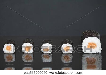 Stock Image - Maki sushi in a row, one piece larger than the others. Fotosearch