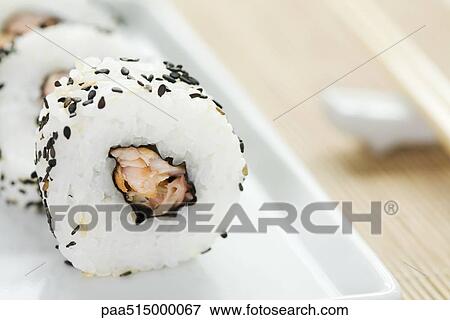 Stock Photo - Maki sushi rolled in black sesame seeds, close-up. Fotosearch