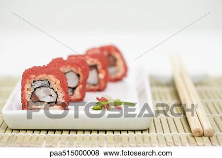 Stock Photo - Maki sushi rolled in red flying fish roe, close-up. Fotosearch
