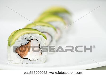 Stock Image - Row of maki sushi on sushi plate, close up. Fotosearch