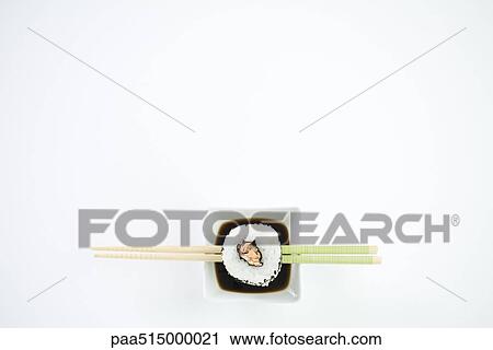 Single piece of maki sushi resting on chopsticks over dish of soy sauce, overhead view View Large Photo Image Stock Image - Single piece of maki sushi resting on chopsticks over dish of soy sauce, overhead view. Fotosearch