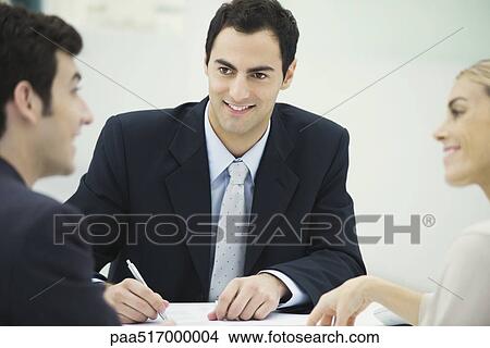 Business associates having discussion, smiling at each other, man taking notes View Large Photo Image Picture - Business associates having discussion, smiling at each other, man taking notes. Fotosearch