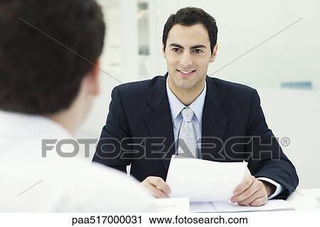 Businessman holding document, smiling at client View Large Photo Image Stock Image - Businessman holding document, smiling at client. Fotosearch