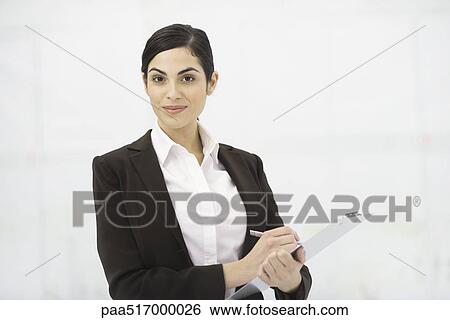 Businesswoman holding clipboard, taking notes, smiling at camera, portrait View Large Photo Image Stock Photograph - Businesswoman holding clipboard, taking notes, smiling at camera, portrait. Fotosearch