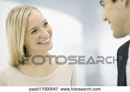 Stock Photo - Colleagues chatting, smiling at each other. Fotosearch