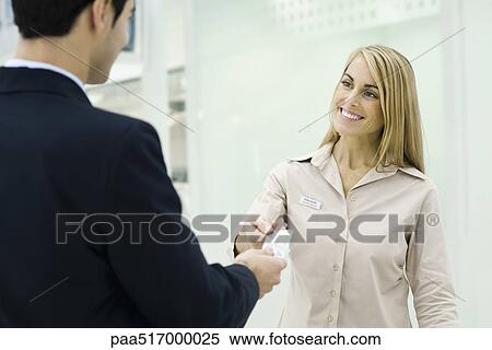 Stock Photography - Man giving credit card to smiling customer service representative. Fotosearch