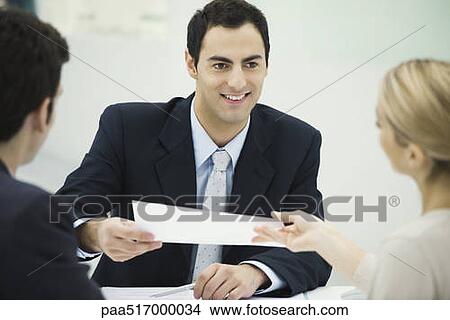 Meeting between professional and clients, man passing document to woman View Large Photo Image Picture - Meeting between professional and clients, man passing document to woman. Fotosearch