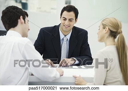 Stock Image - Meeting between professional and clients, together reviewing document. Fotosearch