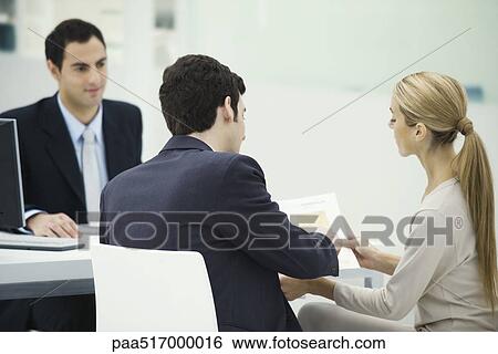 Professional meeting with clients, couple analyzing document together View Large Photo Image Stock Photograph - Professional meeting with clients, couple analyzing document together. Fotosearch