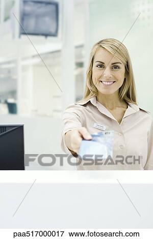 Stock Photo - Travel agent holding out ticket, smiling at camera, personal perspective. Fotosearch