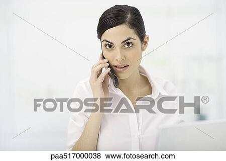Stock Photo - Woman talking on cell phone, looking at camera. Fotosearch