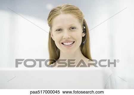 Stock Photography - Woman wearing headset smiling at camera, portrait. Fotosearch
