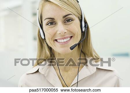 Stock Photography - Woman wearing headset, smiling at camera, portrait. Fotosearch