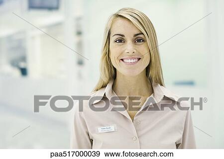 Stock Photo - Woman wearing nametag smiling at camera, portrait. Fotosearch