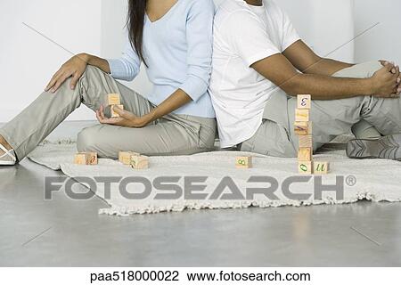 Couple sitting on the ground with building blocks, cropped view View Large Photo Image Stock Image - Couple sitting on the ground with building blocks, cropped view. Fotosearch