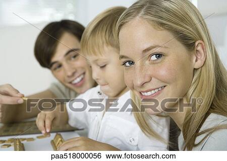 Stock Photograph - Family playing board game, mother smiling at camera. Fotosearch