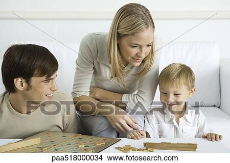 Picture - Family playing board game together. Fotosearch