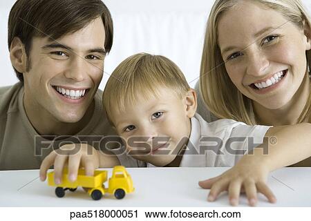 Family smiling at camera, boy playing with toy truck View Large Photo Image Stock Image - Family smiling at camera, boy playing with toy truck. Fotosearch