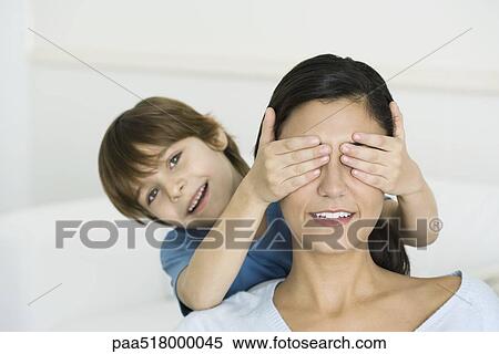 Little boy covering his mother's eyes with his hands, smiling at camera View Large Photo Image Stock Photography - Little boy covering his mother's eyes with his hands, smiling at camera. Fotosearch