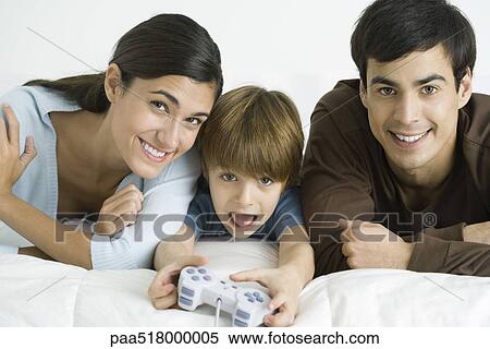 Stock Photography - Little boy playing video game, parents watching. Fotosearch