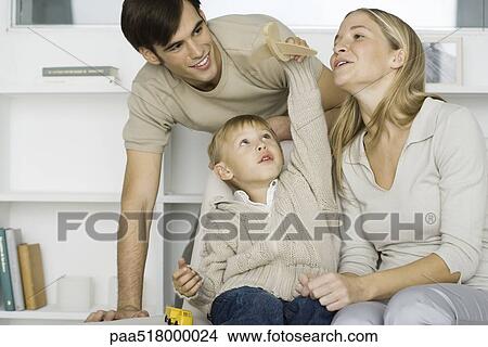Little boy playing with toy airplane, parents watching View Large Photo Image Picture - Little boy playing with toy airplane, parents watching. Fotosearch