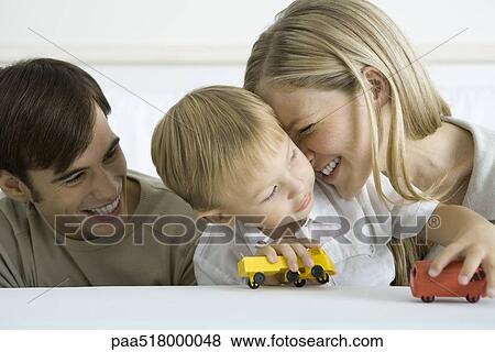 Little boy sitting with parents, playing with toy trucks, mother nuzzling his cheek View Large Photo Image Stock Photo - Little boy sitting with parents, playing with toy trucks, mother nuzzling his cheek. Fotosearch