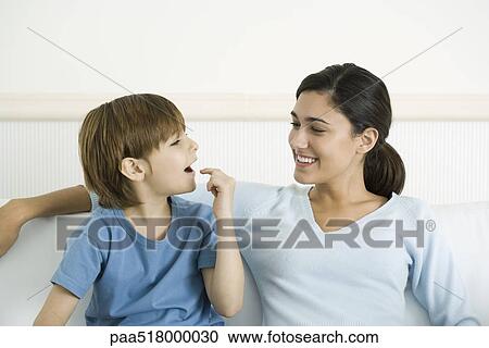 Mother and son sitting together, boy pointing to open mouth View Large Photo Image Stock Image - Mother and son sitting together, boy pointing to open mouth. Fotosearch