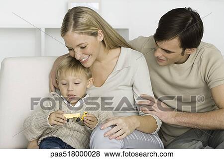 Parents and young son looking at toy truck, smiling View Large Photo Image Stock Photo - Parents and young son looking at toy truck, smiling. Fotosearch