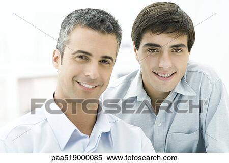 Adult son looking over father's shoulder, both smiling at camera View Large Photo Image Stock Photography - Adult son looking over father's shoulder, both smiling at camera. Fotosearch