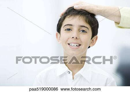 Adult's hand on child's head, boy smiling at camera, cropped view View Large Photo Image Stock Photograph - Adult's hand on child's head, boy smiling at camera, cropped view. Fotosearch