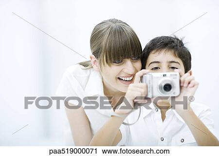 Boy taking picture with camera, mother leaning over his shoulder, smiling View Large Photo Image Stock Image - Boy taking picture with camera, mother leaning over his shoulder, smiling. Fotosearch