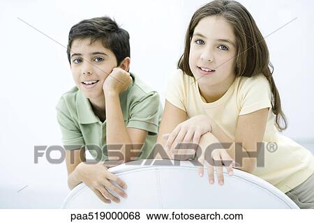 Brother and sister leaning against chair, smiling, portrait View Large Photo Image Stock Photo - Brother and sister leaning against chair, smiling, portrait. Fotosearch