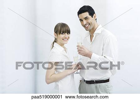 Couple holding champagne flutes, smiling at camera View Large Photo Image Stock Image - Couple holding champagne flutes, smiling at camera. Fotosearch